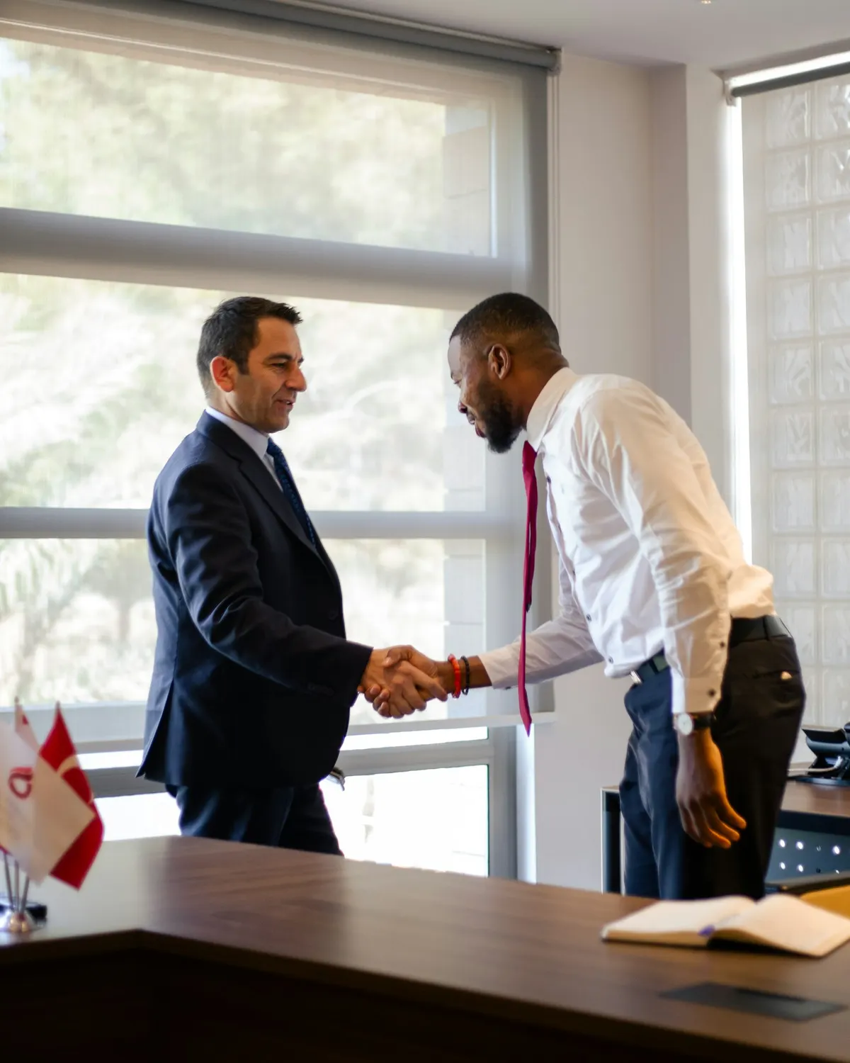 Dos empresarios dandose la mano sobre un escritorio