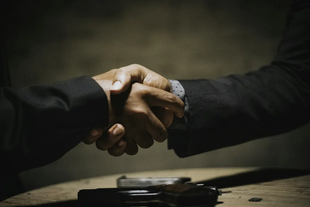 Dos personas dandose la mano sobre una mesa de madera