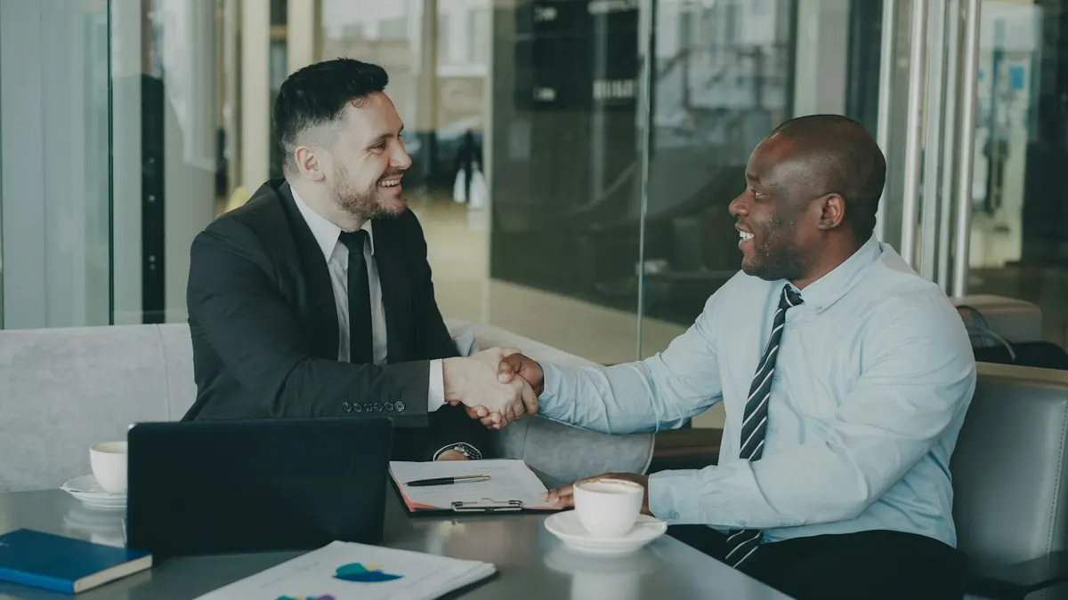 Dos empresarios dandose la mano sobre una mesa