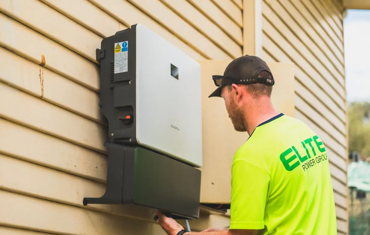 Tecnico instalando un inversor solar en el exterior de una vivienda