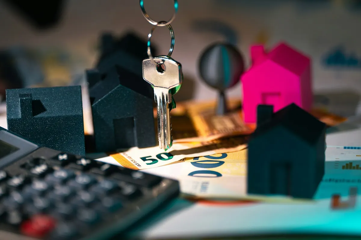 Calculadora y maqueta de una casa sobre una mesa