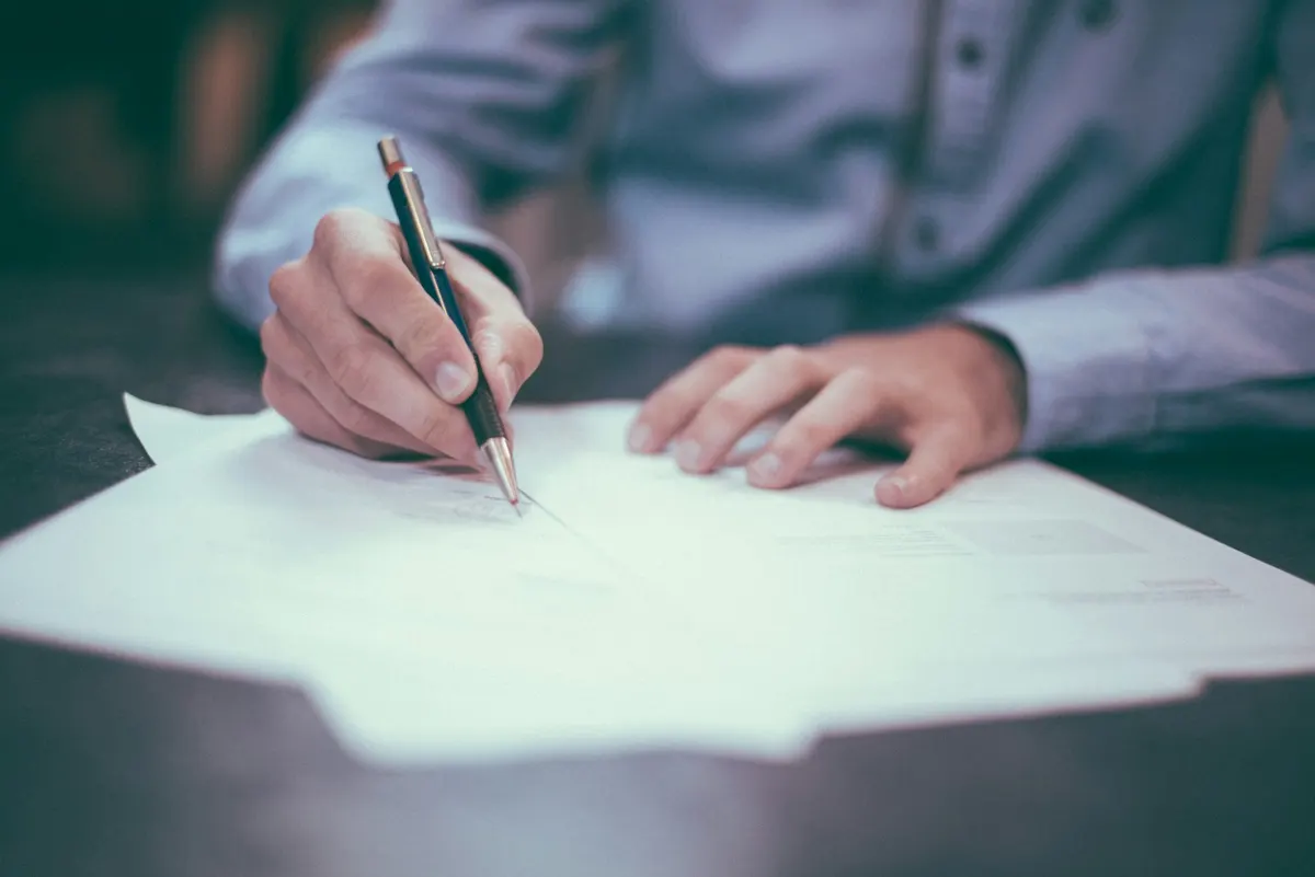 Persona leyendo y firmando un documento